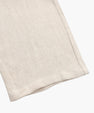 Close-up of beige linen fabric with visible texture and stitched hem detail