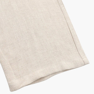 Close-up of beige linen fabric with visible texture and stitched hem detail