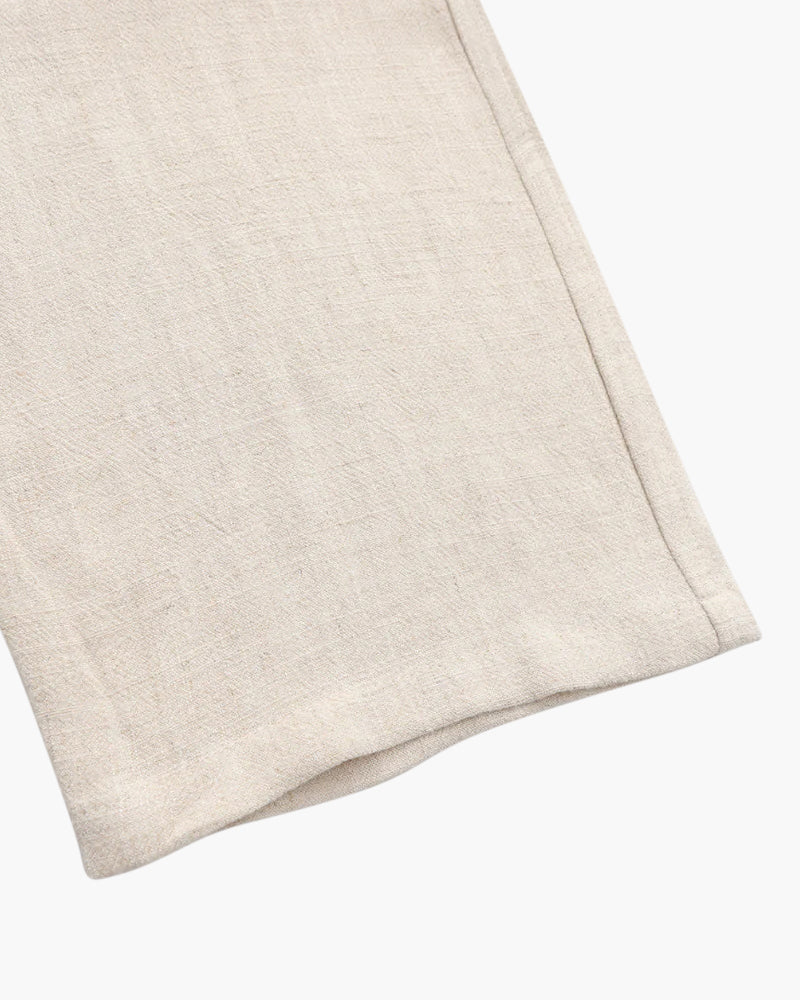 Close-up of beige linen fabric with visible texture and stitched hem detail