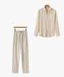 Beige loungewear set with long sleeve button-up shirt and drawstring pants hanging on wooden hangers