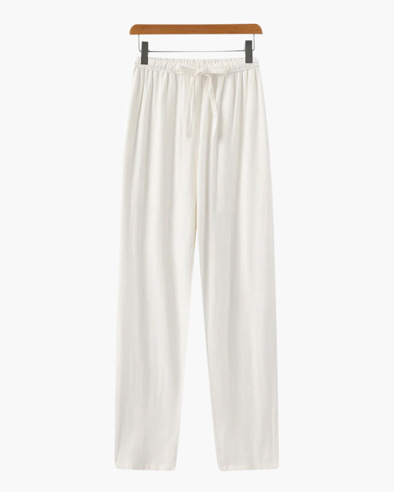 White casual loose fit pants with elastic waistband and drawstring hanging on wooden hanger